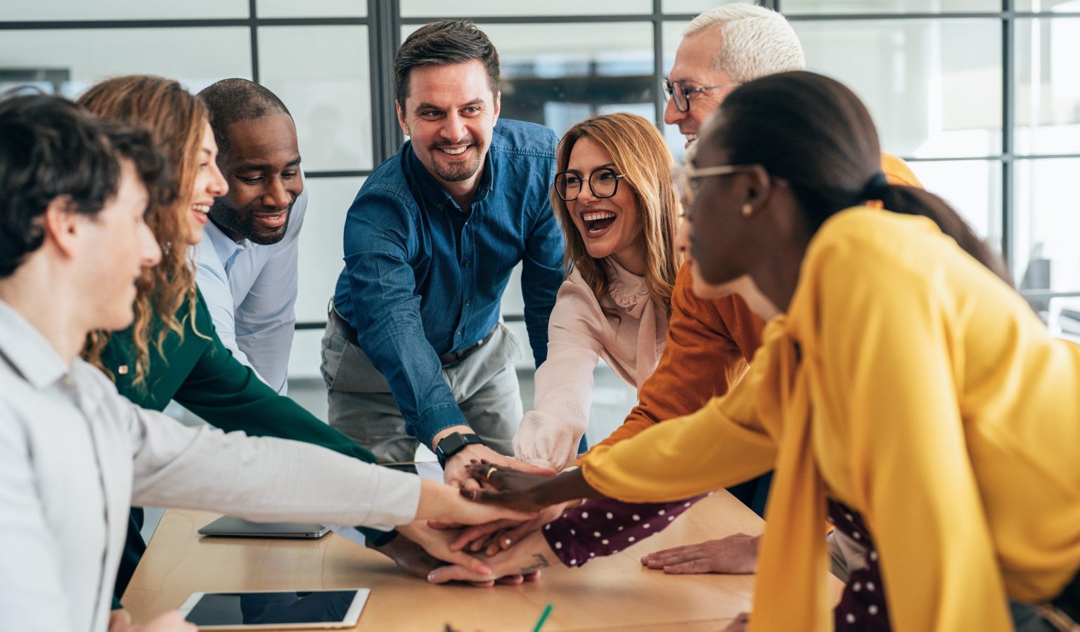 Successful business people stacking hands in the office. Shot of group of business people celebrating their success. Cheerful business team holding their hands together. They looking happy and excited